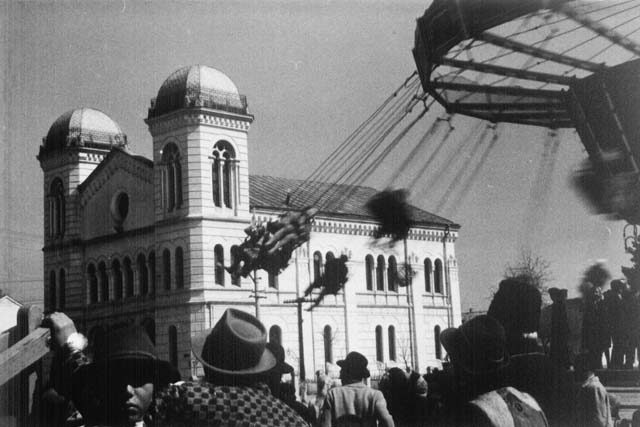 The Great Temple seen behind a fairground swing ride, with a crowd in the foreground