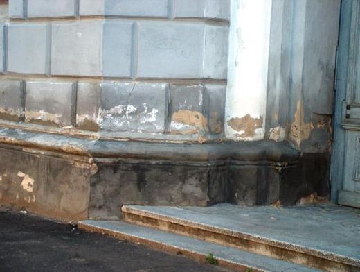 The damaged base of the wall near the entrance steps