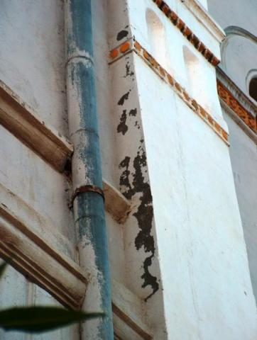 A drainpipe and the flaking plaster of the façade